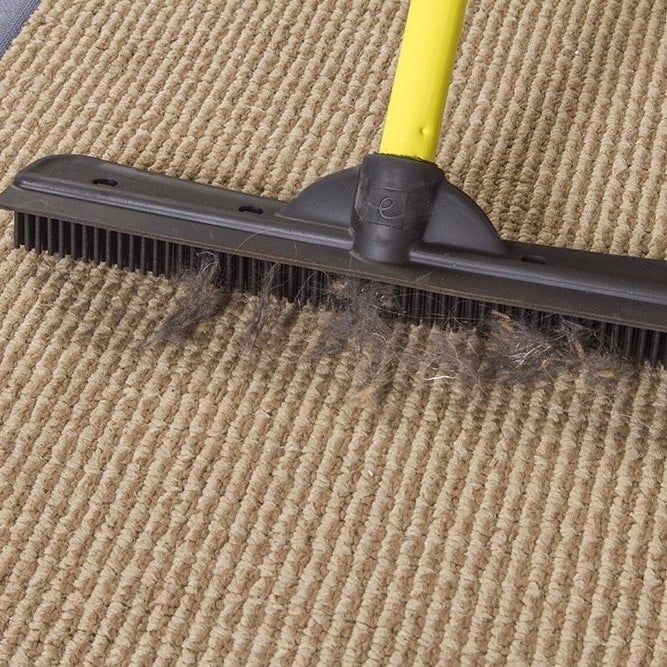 The broom picking up pet hair from the carpet.