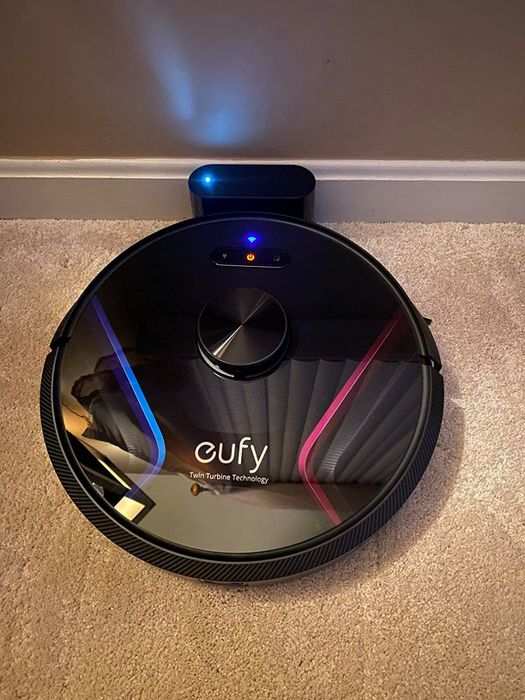 A reviewer photo showing the robotic vacuum docked and charging