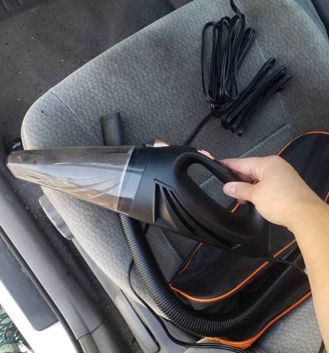 Reviewer holding the portable vacuum with the cord and bag in the background