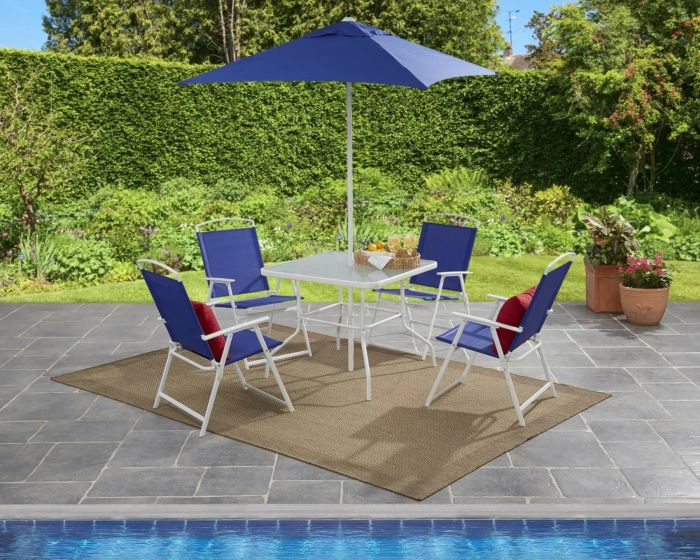 White and blue chairs, a glass table, and a matching blue umbrella set up on a beautifully decorated pool deck.