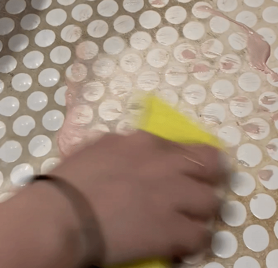 GIF of Britt using The Pink Stuff to scrub stains from white grout