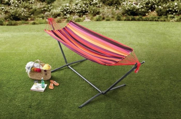 A striped hammock set up in a backyard, complete with a picnic setup, creating the perfect cozy retreat.