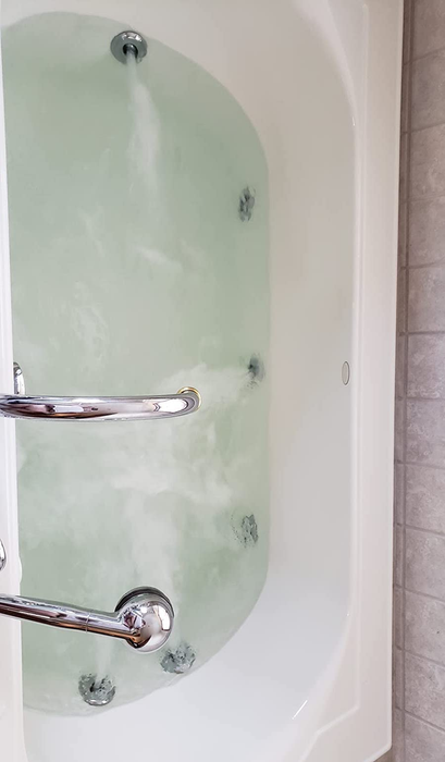 A reviewer’s after photo of a jetted tub filled with pristine, clear water after being cleaned