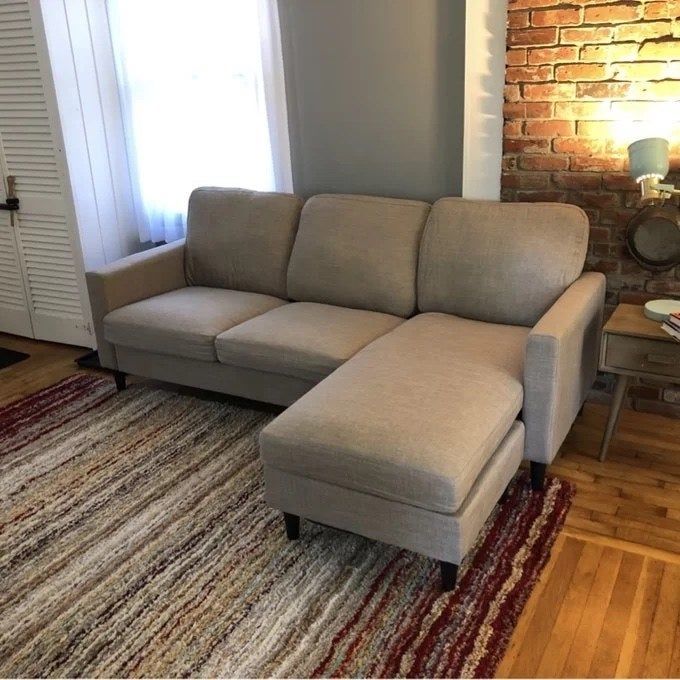 a beige sectional in a living room with exposed brick walls