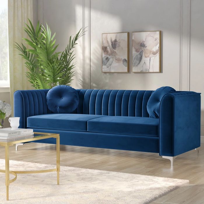 a navy velvet sofa with metallic legs placed in a living room
