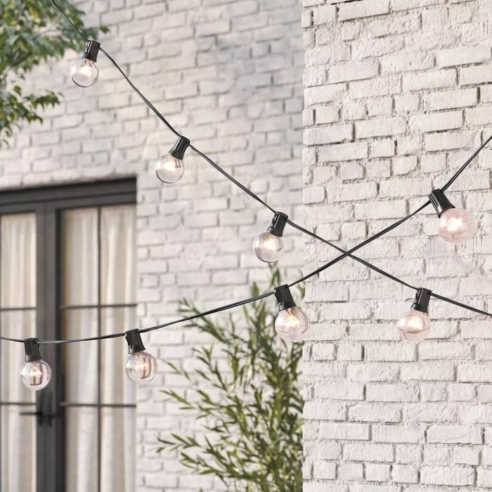 A string of outdoor lights draped across a brick wall, perfect for creating a cozy patio or garden ambiance.