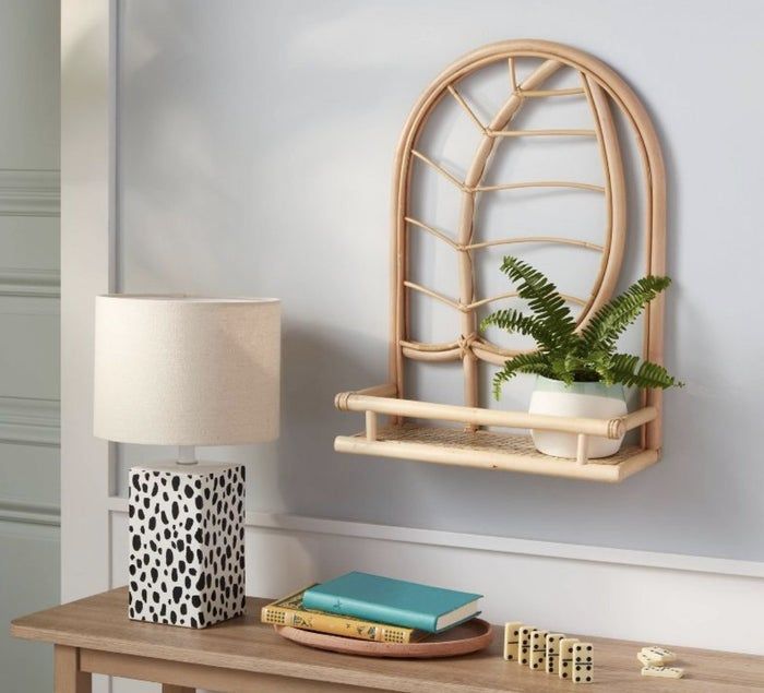 A rattan shelf featuring a leaf design, holding a small plant