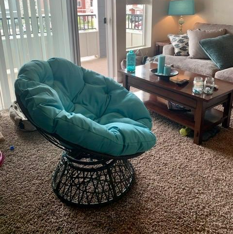 Reviewer image of the side view of a product featuring a light blue cushion and black wicker base on a carpet