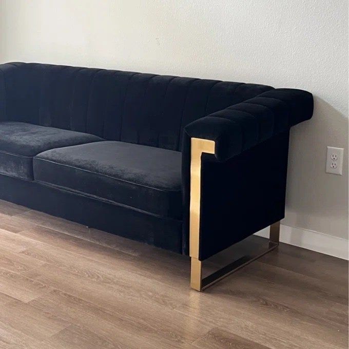 a black and gold sofa placed against a clean white wall