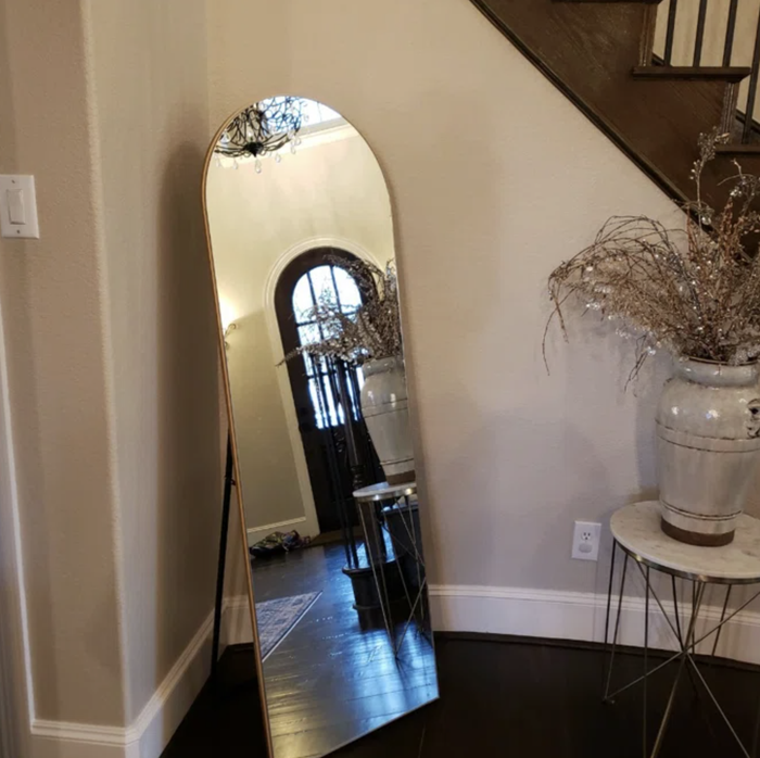 the gold standing mirror placed in a foyer