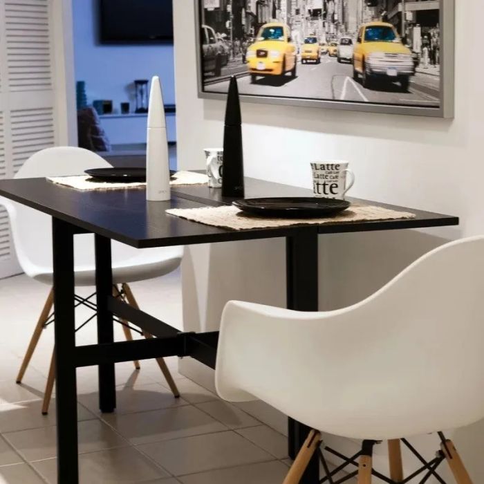 A dining table with white chairs, black-and-white tableware, and coffee mugs marked with the word