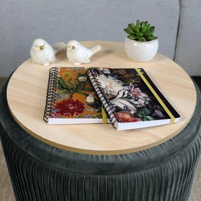 Two notebooks rest on a round ottoman table.