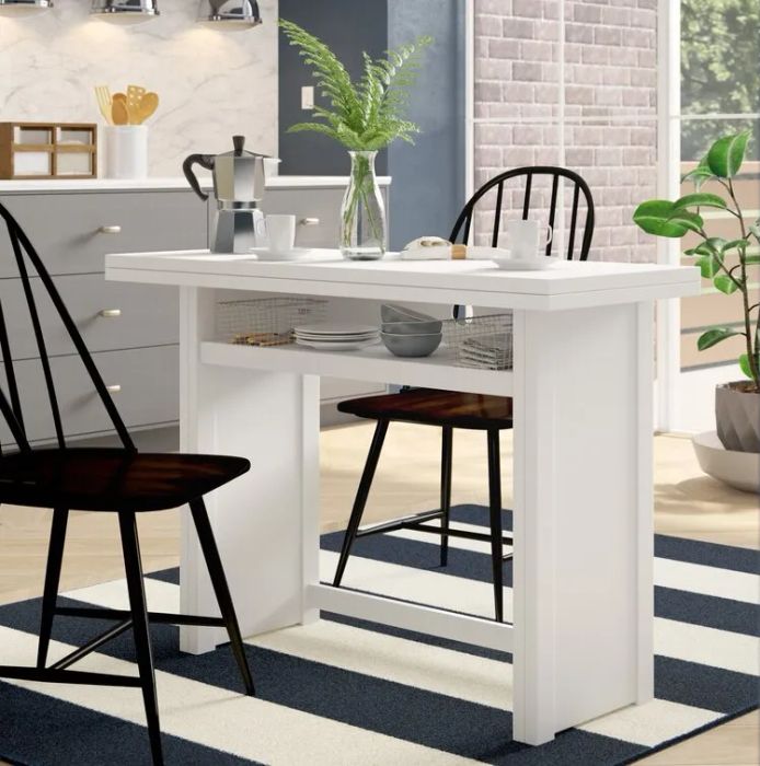 A white trestle table with a built-in shelf underneath, flanked by two black chairs on either side.