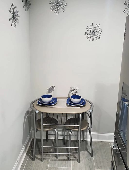 a reviewer's photo of a silver bistro table with two matching chairs tucked underneath it