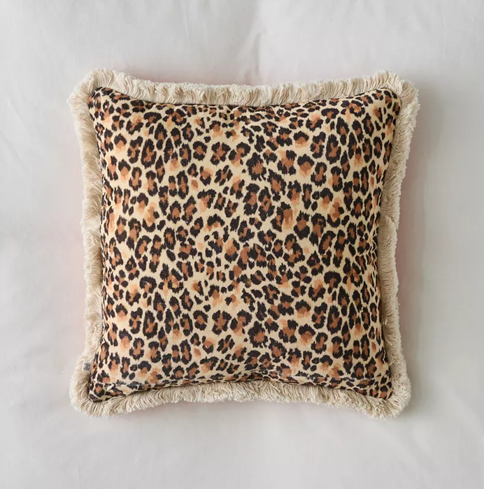 A leopard print pillow with fringe details set against a white background, highlighted in a shopping guide.