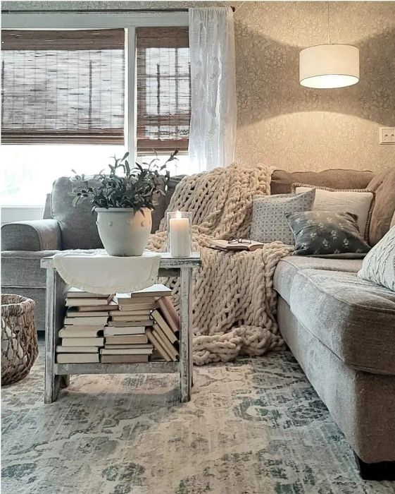 A cozy living room featuring a grey sofa, a knit throw blanket, and pillows.