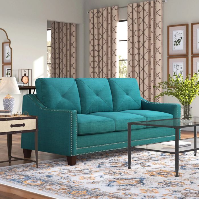 A teal sofa with metal tufts in a cozy living room.