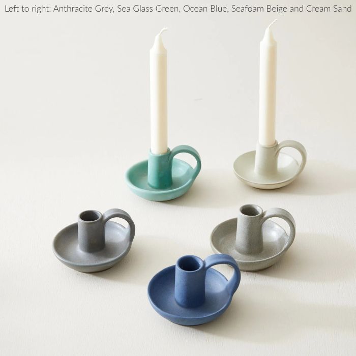 A set of five ceramic candle holders in various colors and sizes, each holding a white candle. The colors from left to right: Anthracite Grey, Sea Glass Green, Ocean Blue, Seafoam Beige, and Cream Sand.