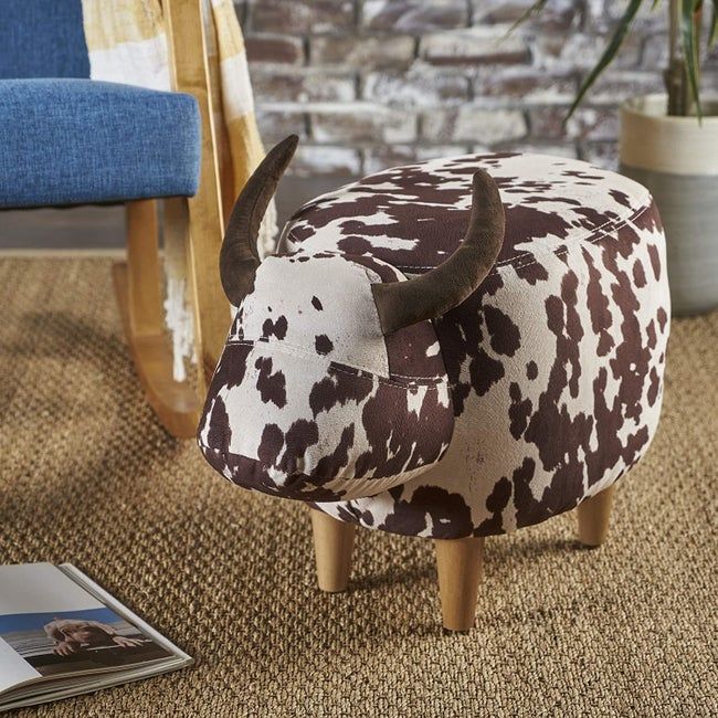 The cow-print ottoman featuring four wooden legs and two plush horns