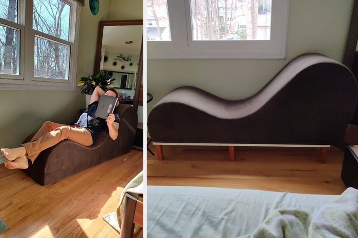 Reviewer lounging on a brown curved chair, reading a book, side view of the chair resting on a wooden elevated base