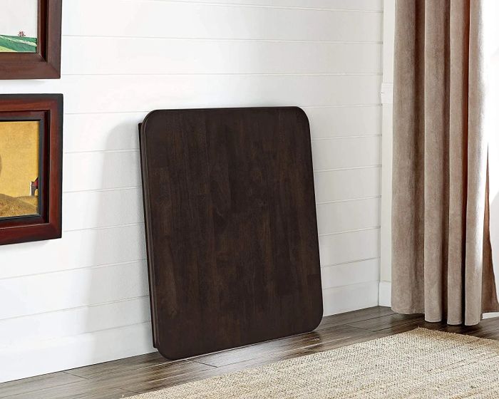 a dark wood square dining table folded neatly against a wall