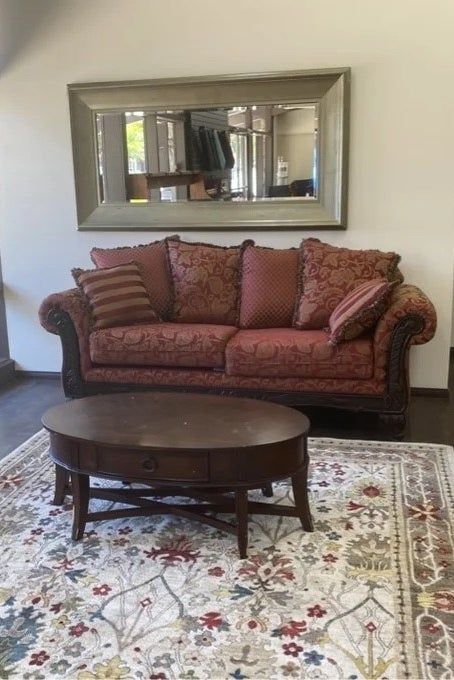 a paisley sofa in red and yellow tones placed in a living room alongside a floral rug