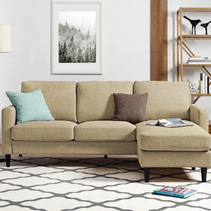 a beige sectional placed on a white and gray geometric-patterned rug