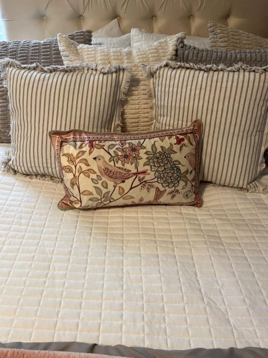 Decorative throw pillows with various designs are neatly arranged on a well-made bed featuring a quilted blanket.