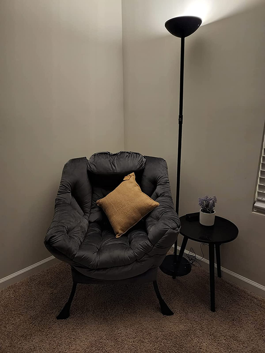 Reviewer image of a dark gray tufted plush chair with a yellow pillow resting beside a side table and floor lamp