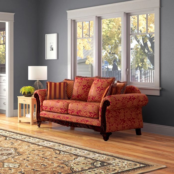 a vibrant red and yellow paisley sofa in a living room, complemented by a cozy rug
