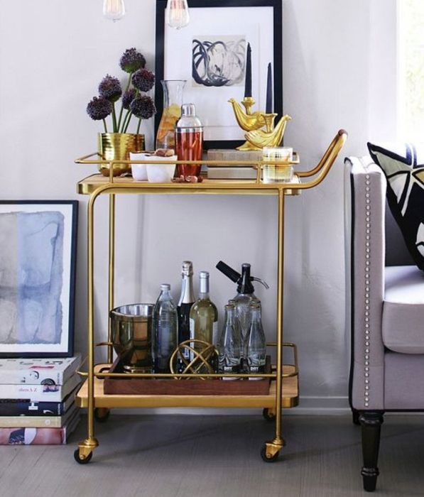 A golden bar cart with liquor bottles elegantly displayed on it
