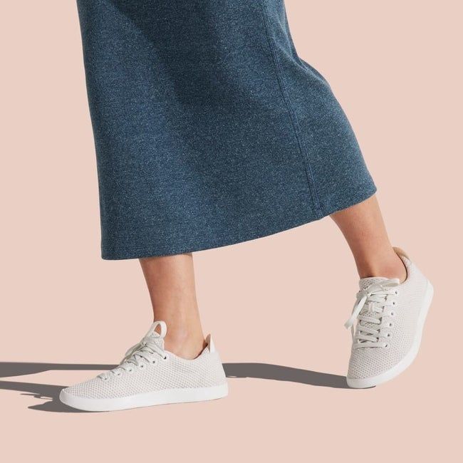 Model wearing white sneakers paired with a dark gray midi skirt