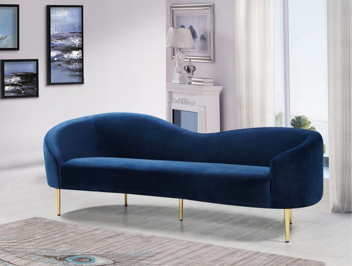 a navy blue upholstered sofa with golden legs placed in a living room