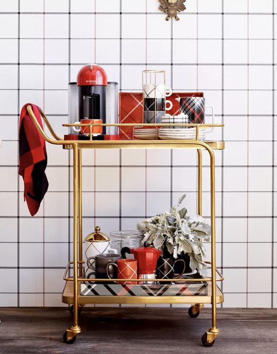A chic gold bar cart featuring a coffee machine, cups, and various decorative items, neatly arranged to inspire your home decor style