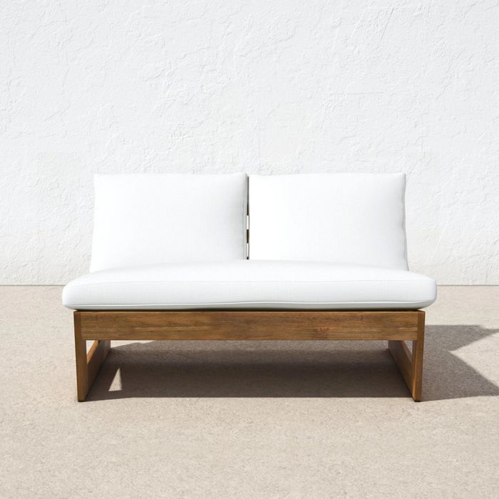 a white outdoor loveseat placed outside against a white wall