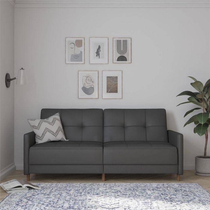 a dark gray faux-leather tufted convertible sofa in a modern living room