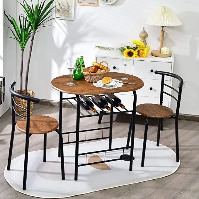 a brown and black bistro table featuring two matching chairs with three wine bottles placed on a rack underneath