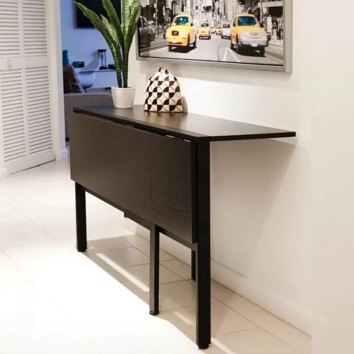 A foldable console table in a sleek white room, decorated with a potted plant and a patterned vase. Wall art showcasing yellow taxis completes the scene.