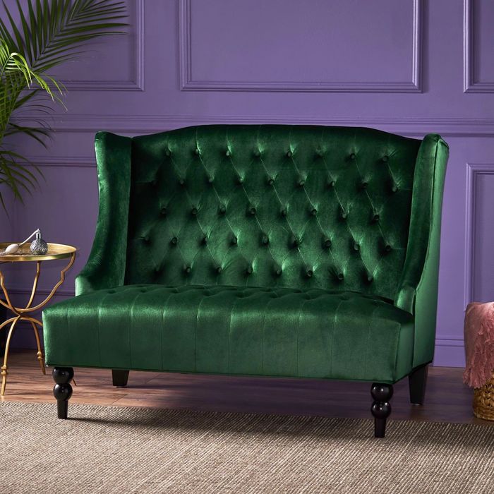 an emerald loveseat against a striking purple wall
