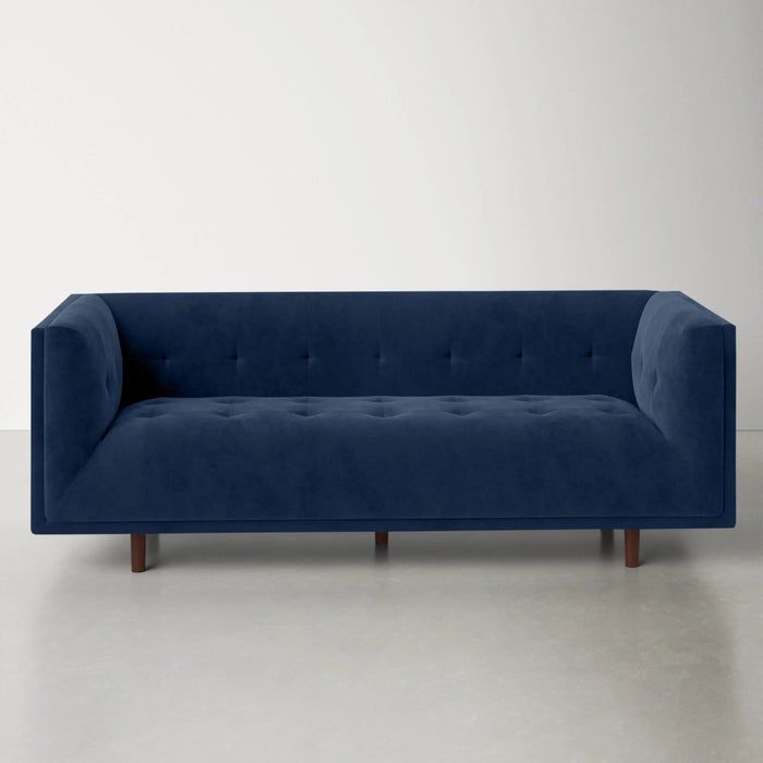 a sapphire velvet tufted sofa with brown wooden legs for a chic, sophisticated look