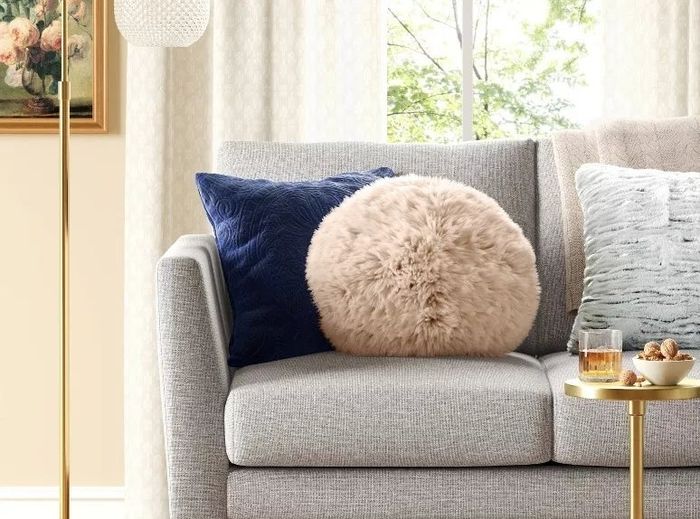 the fluffy faux fur round pillow, resting comfortably on a couch