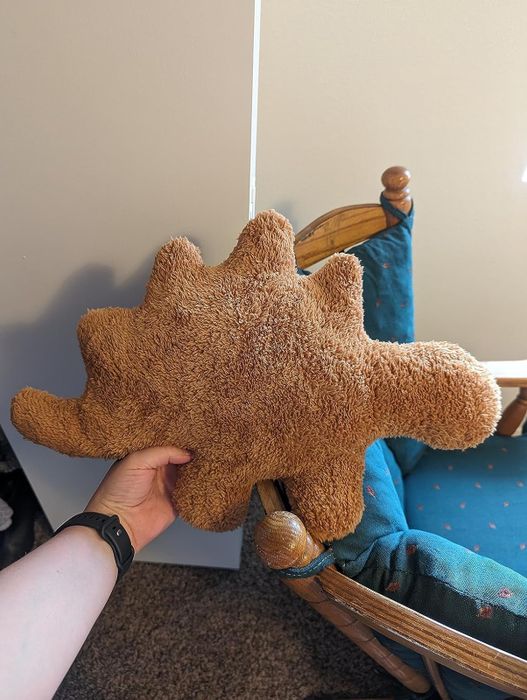 A person holding a stegosaurus nugget plush.