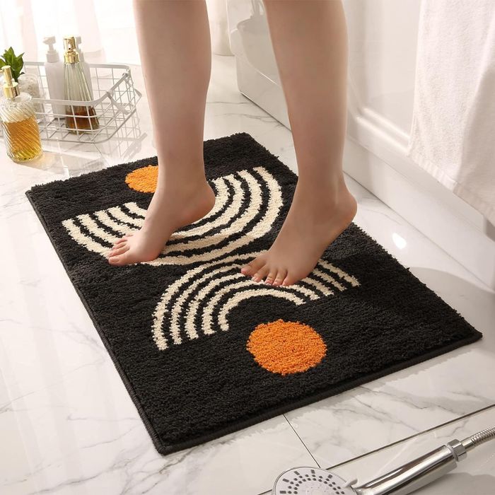 A person stepping onto the black and white rug.