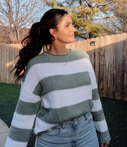 Person outdoors sporting a mint and white striped sweater paired with high-waisted jeans