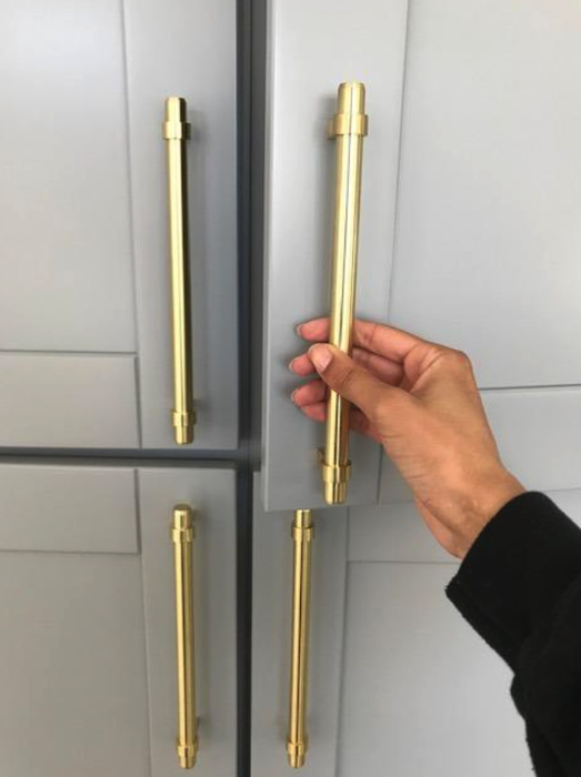 A reviewer pulling a gold handle on a kitchen cabinet