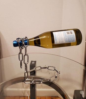 A wine bottle suspended mid-air by a sleek holder.
