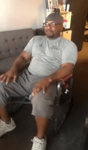 Video of a reviewer relaxing in a foldable outdoor rocking chair, dressed in a gray shirt, dark gray shorts, and white sneakers