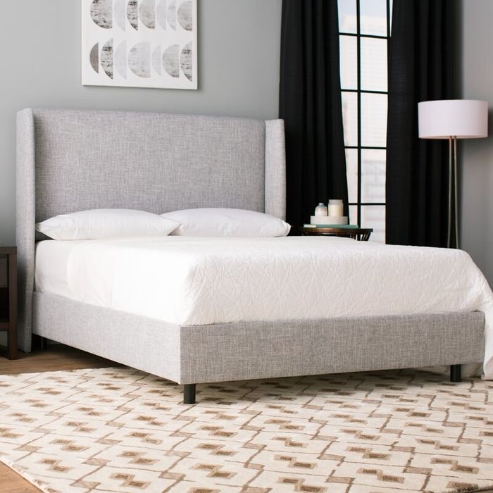 A chic gray upholstered bed frame with a large, inviting headboard.