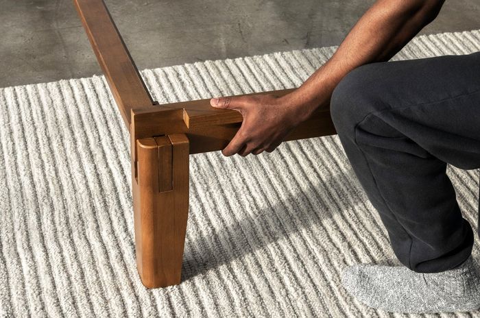close-up view of the joinery, with someone assembling the bed