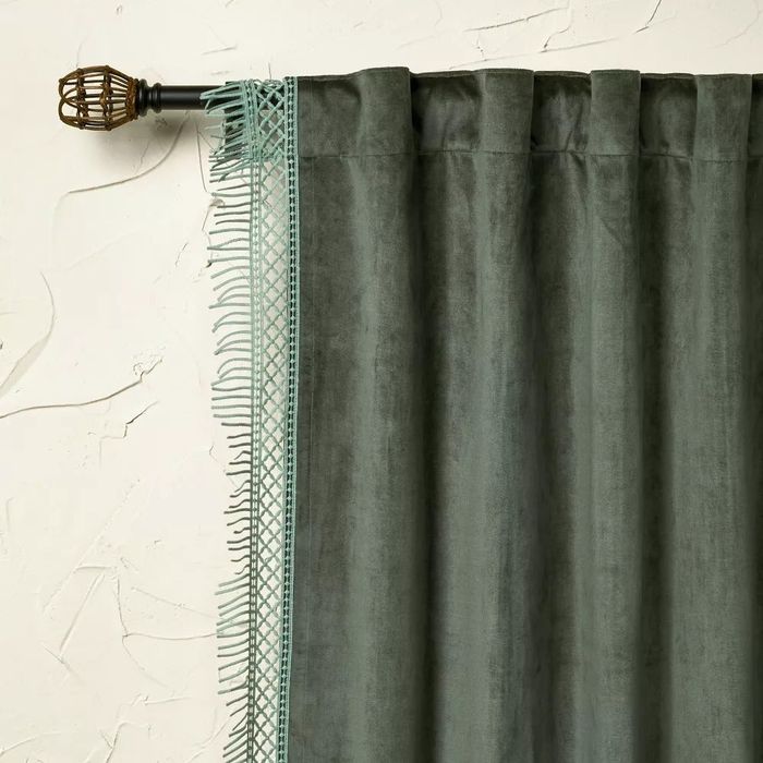 A rich green velvet curtain hanging on a gold rod